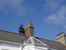Roofer working at a chimney flashing on a rooftop