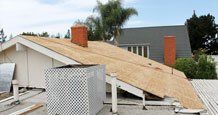 Residential roof mid-installation with shingle bundles and chimney